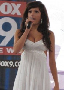 Casey Carlson on stage singing wearing a white dress