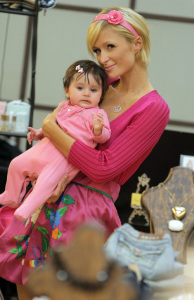 Paris Hilton carries a cute customer's baby daughter as she shops for clothes at a store