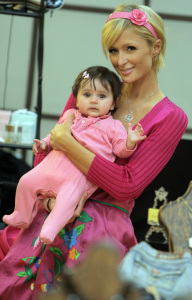 Paris Hilton carries a cute customer's baby daughter as she shops for clothes at a store