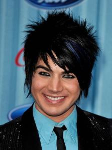 Adam Lambert picture wearing a light blue shirt under a black suit jacket matched with a black neck tie