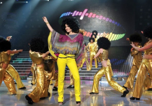 Hilda Khalife in a 70's hair wig dancing on stage with the students at the LBC Star Academy Ninth Prime