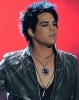 adam Lambert on stage with a large necklace pendant