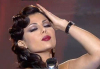 Haifa Wehbe picture during a tv appearance singing on stage in a sixty style makeup and hair wearing a black dress 6